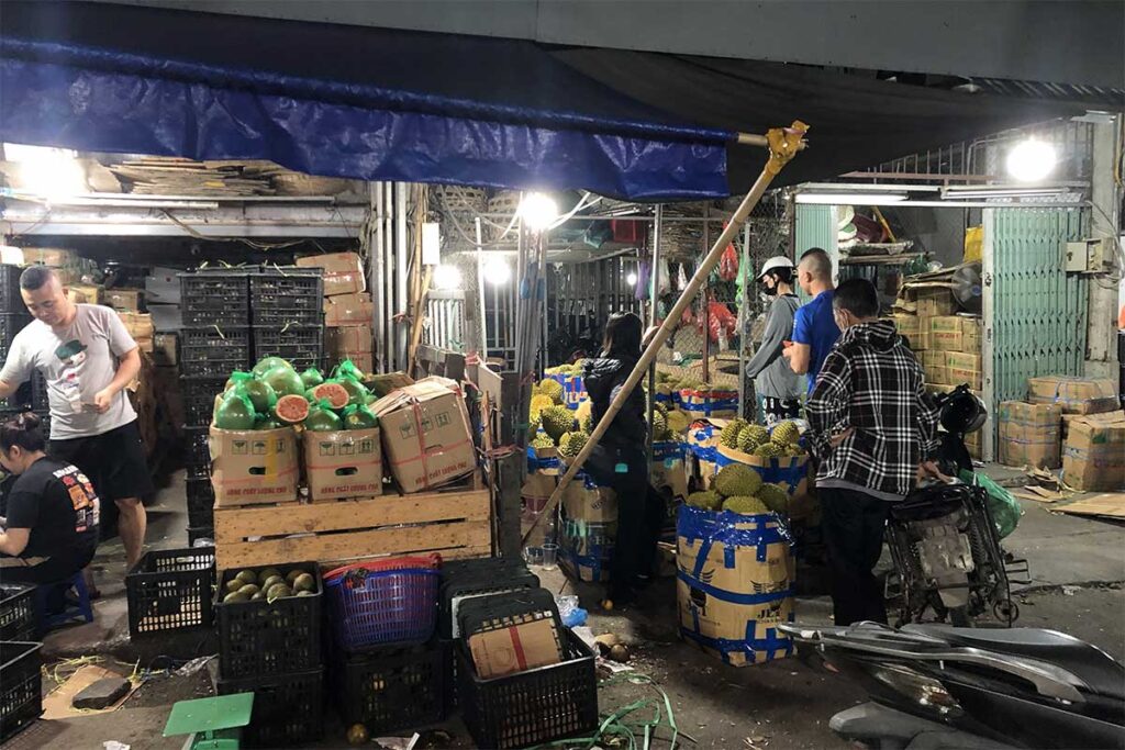 Boxes of fruit stacked on top of eachother ready to be sold at the Long Bien Market