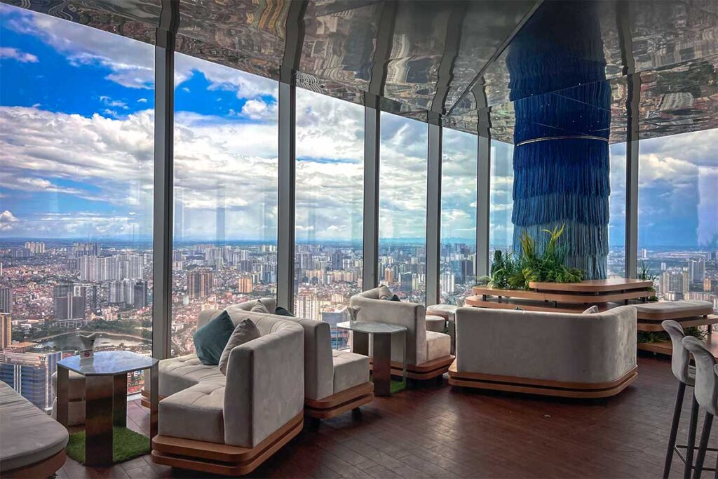 Comfortable chairs and seats facing the large windows overlooking Hanoi of Top of Hanoi rooftop bar