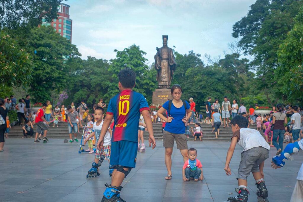 Kids rollerblading at Ly Thai To Park in Hanoi with the statue of Ly Thai To in the background