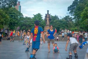 Kids rollerblading at Ly Thai To Park in Hanoi with the statue of Ly Thai To in the background