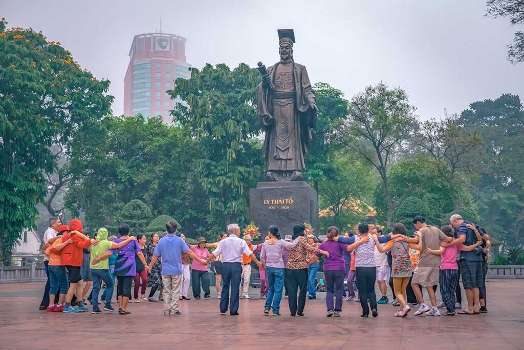 A group of elderly people of Hanoi using the square in front of the statue in Ly Thai To Park for dancing practise 
