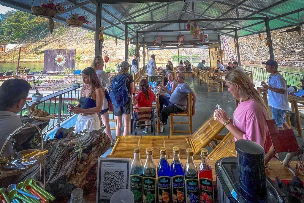 Restaurant area of Mai Chau Floating House with tourists having a drink
