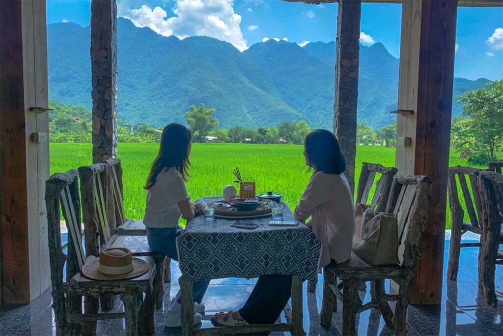 Two woman sitting at a table of Mai Chau Restaurant Countryside overlooking the rice fields