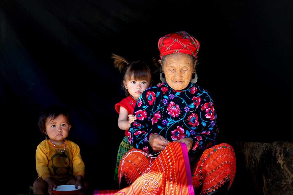 An ethnic woman in traditional clothes and two children in a house in Moc Chau