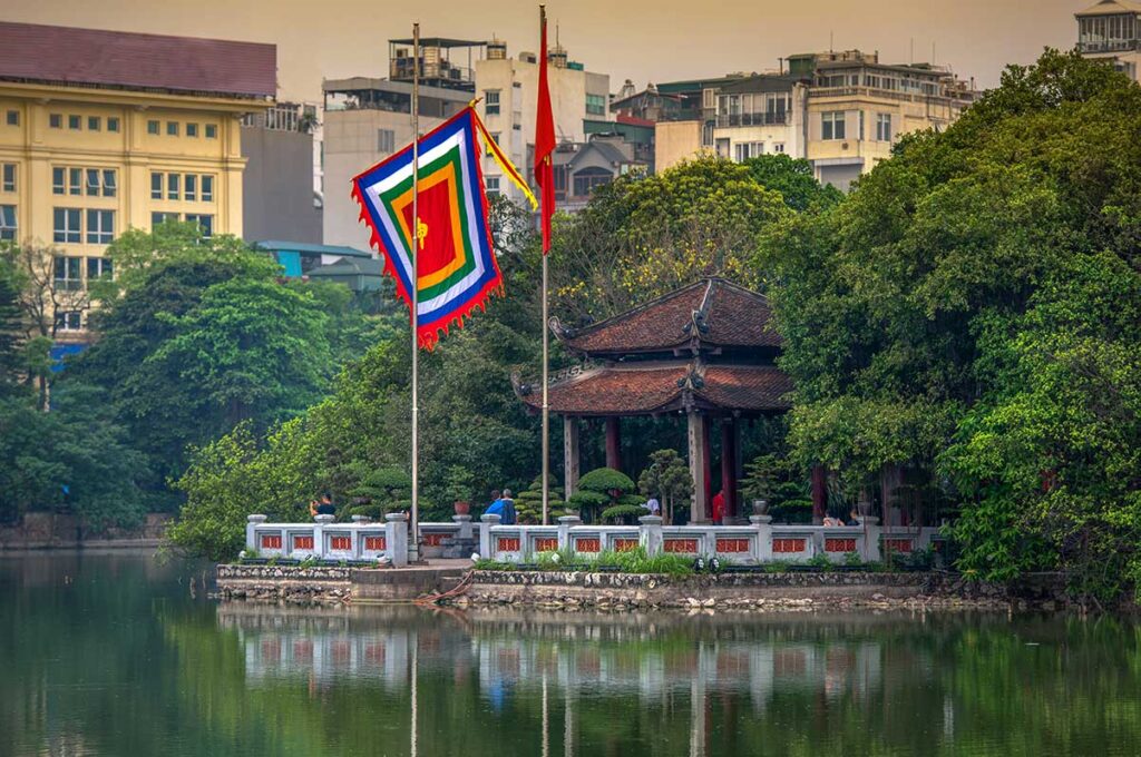 Pavilion on Hoan Kiem Lake near Ngoc Son Temple with Vietnamese and Buddhist flags