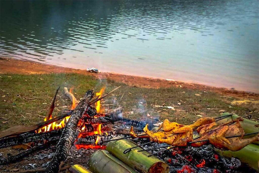 A campfire with roasted chicken next to Pa Khoang Lake