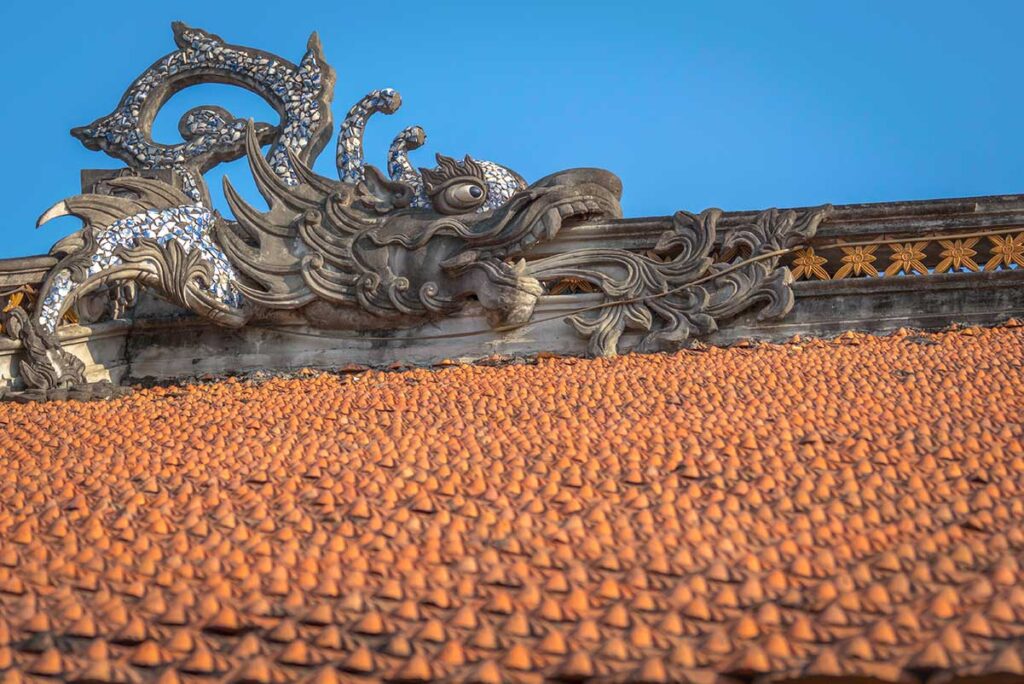 A roof made of clay baked tiles and stone dragon carvings of a local house inside Phu Lang Pottery Village