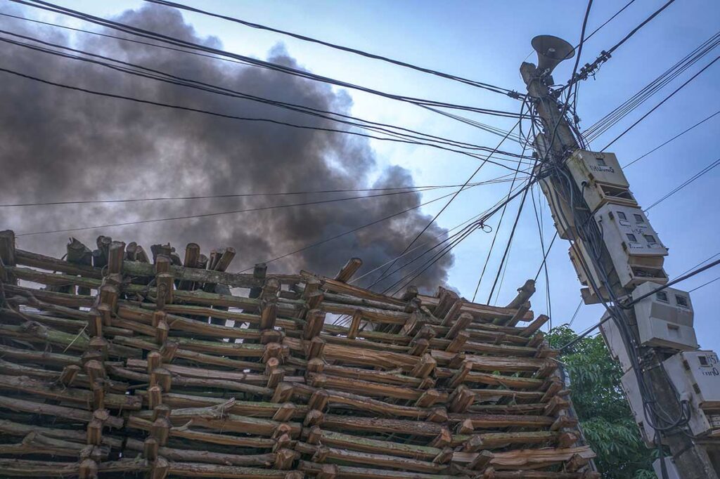Black smoke coming from behind the houses from a burning kiln inside Phu Lang Pottery Village
