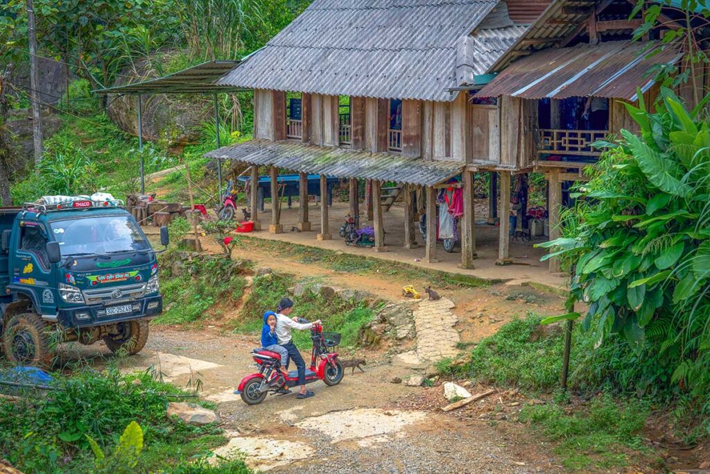 Ethnic stilt house in the jungle along a road with small Vietnamese tuck in Pu Luong Nature Rerve