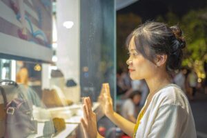 An Asian girl looking through the windows of a fashion store while shopping in Hanoi