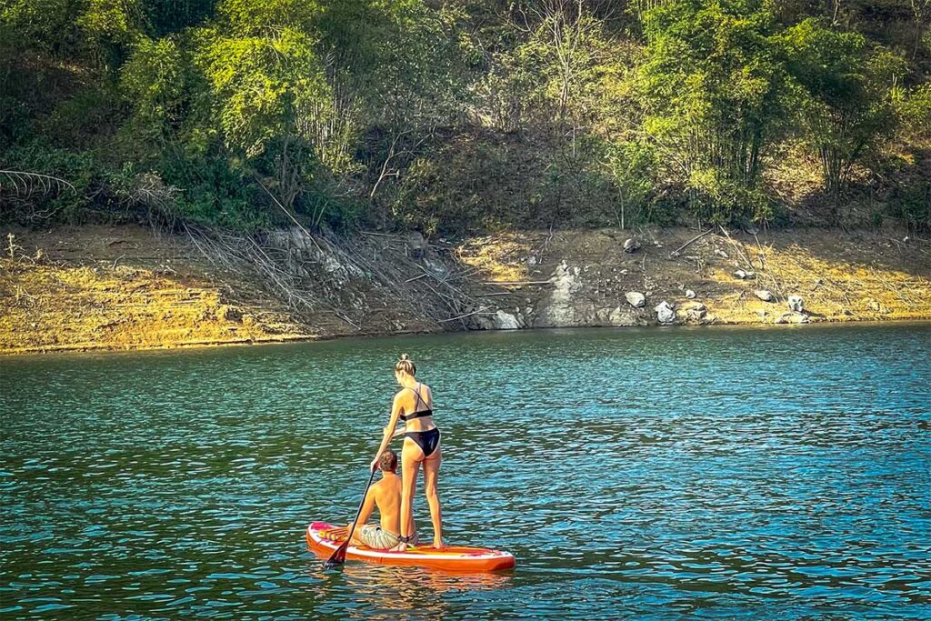 Two tourists are stand-up paddleboarding (SUP) in Hoa Binh Lake