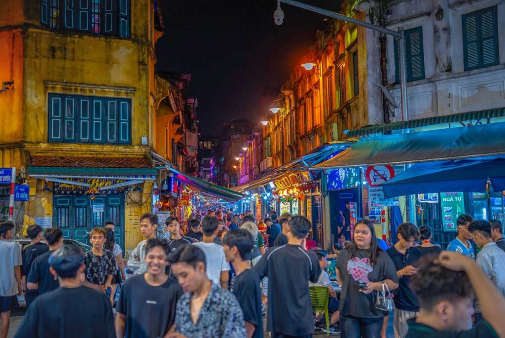 A very busy Ta Hien Street with many people walking at night along the bars in Hanoi Old Quarter