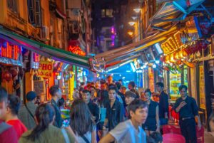 A busy Ta Hien Street at night, also called Bia Hoi street, with lots of locals and tourists walking through the street full of bars in the Old Quarter
