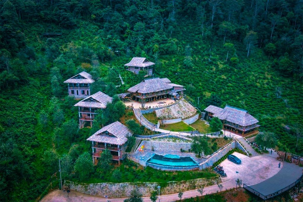Aerial view of Ta Xua Ecolodge with different sleeping buildings, a pool and restaurant area build on a steep mountain