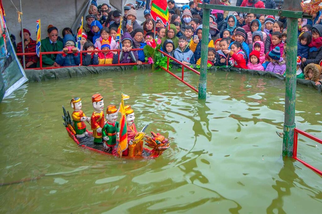 A water puppet show in Thanh Hai Village with lot of kids coming there to watch
