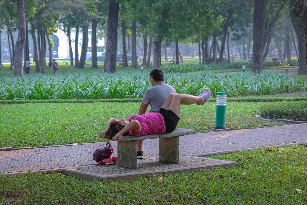 A woman doing sit ups on a bench inside Thong Nhat Park