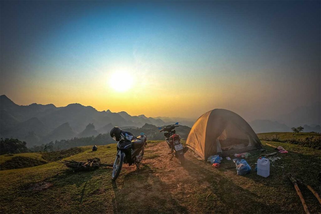Sunset at To Bo Peak with two motorbikes parked and a tent set up for the night