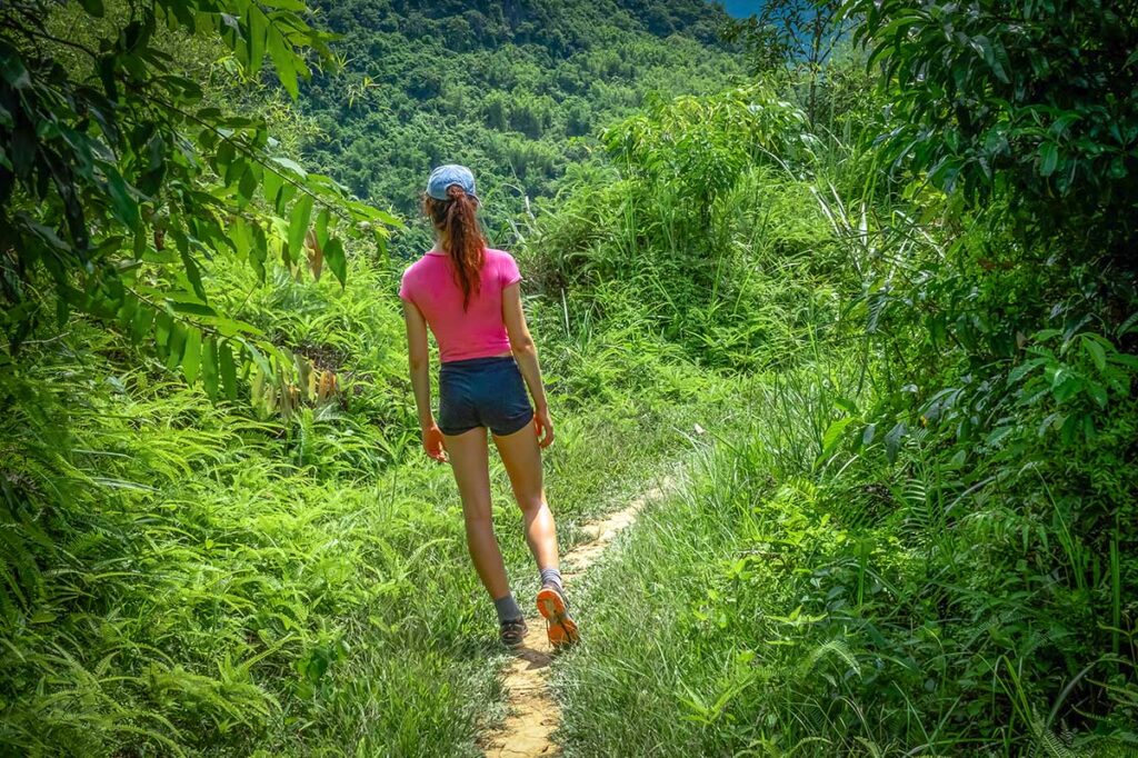 A girl walking through jungle area during a trekking in Pu Luong 