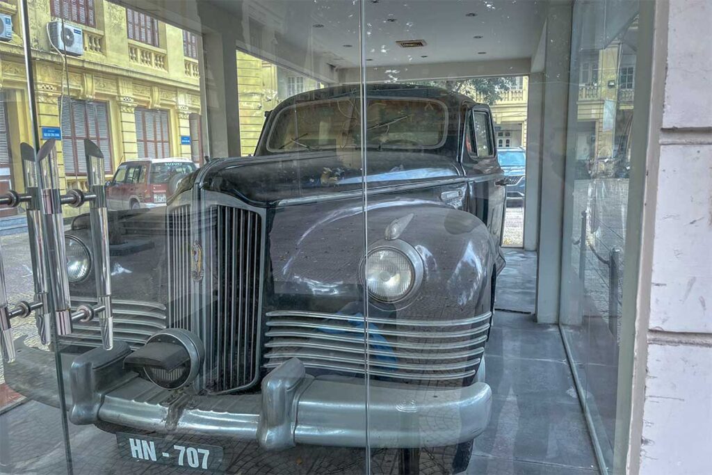 An old vintage car behind glass outside the Vietnam National Museum of History 