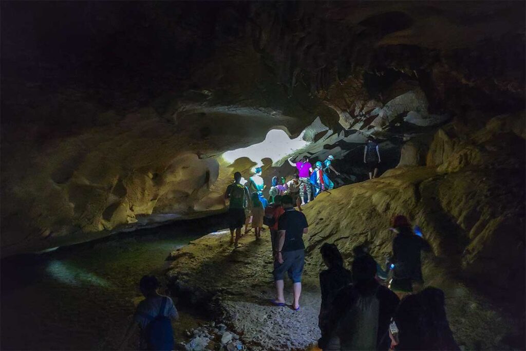 A group of travellers walking with torches in a dark cave inside Xuan Son National Park