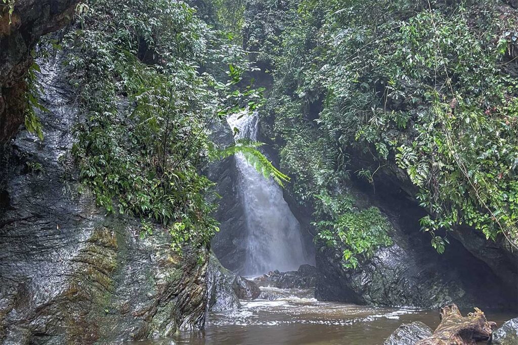 A small local waterfall hidden between rocks and forest inside Xuan Son National Park