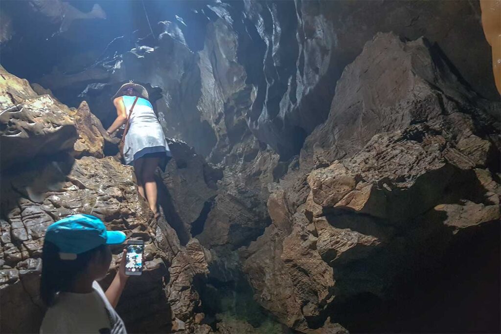 Two girls going through a narrow cave in Xuan Son National Park