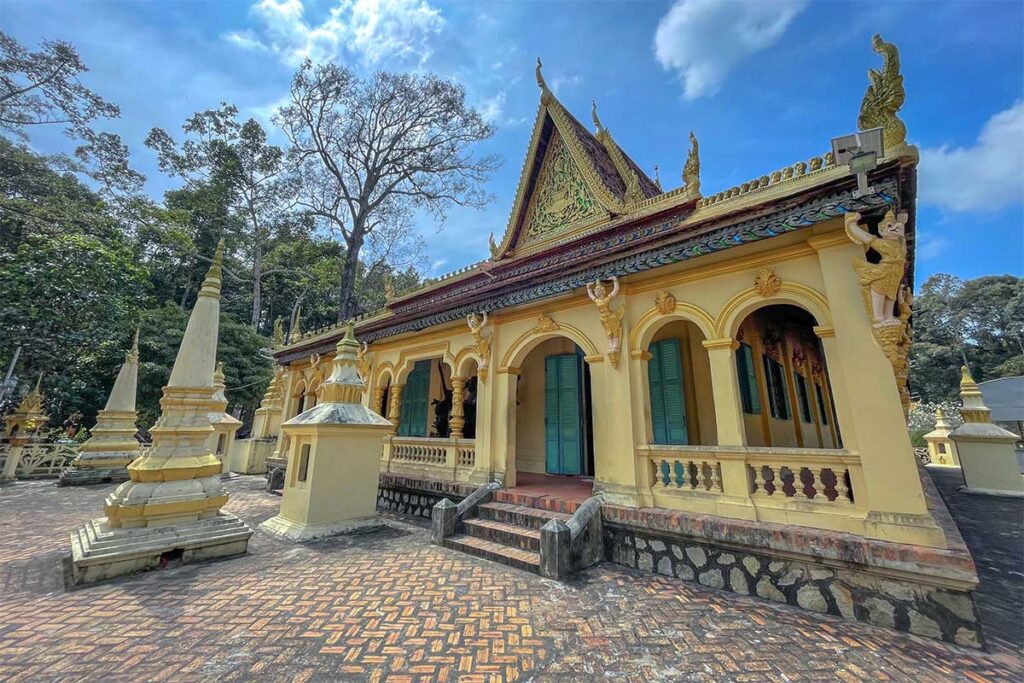 Side view of Ang Pagoda’s main hall in Tra Vinh with golden carvings and green wooden doors.