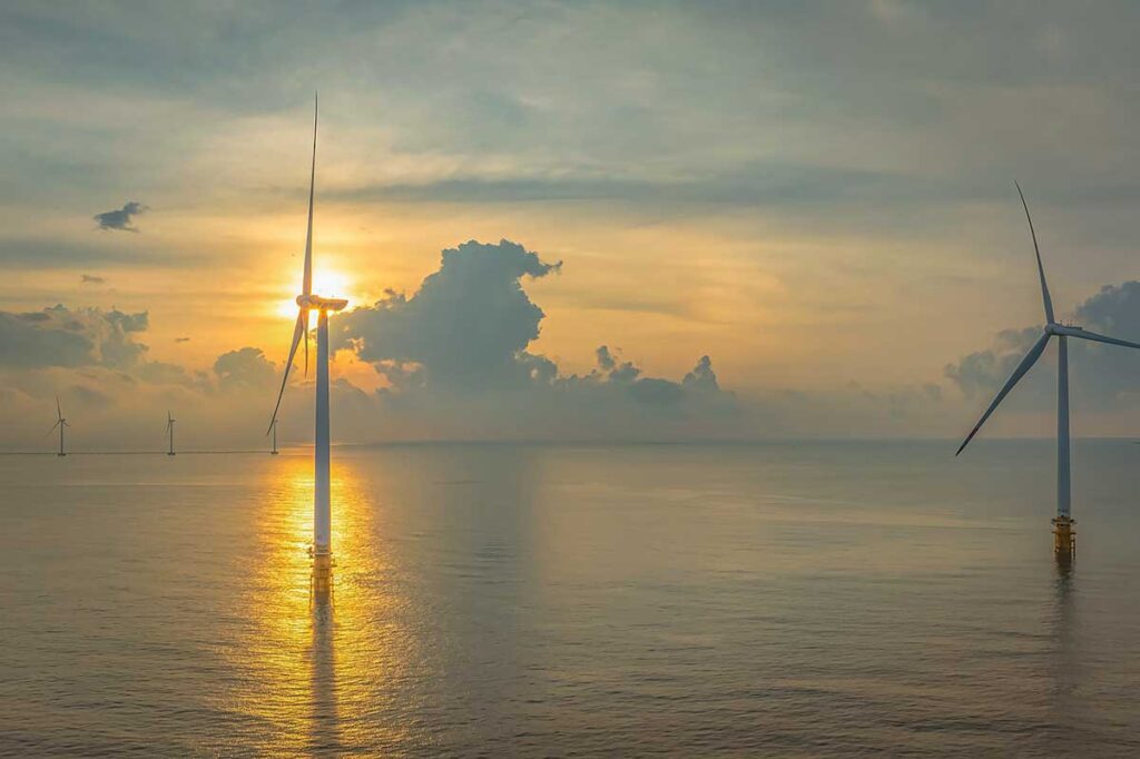 Offshore wind turbines rise from the sea during sunset near Ba Dong Beach in Tra Vinh, highlighting Vietnam’s renewable energy efforts in the Mekong Delta.