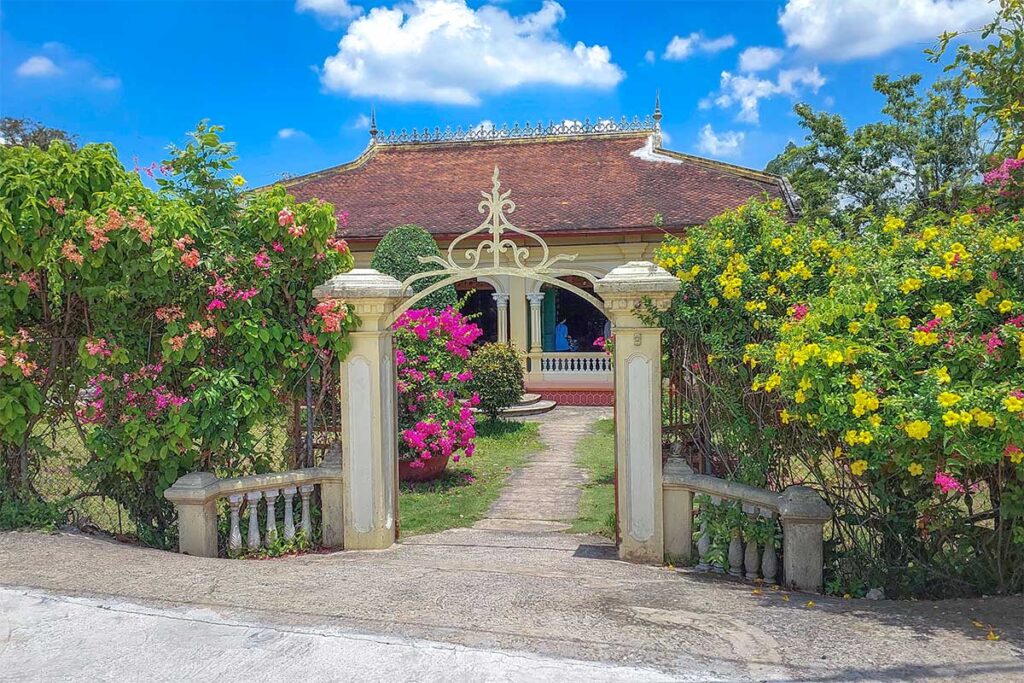 Front gate and flower-filled entrance to Ba Duc Ancient House in Cai Be, Mekong Delta