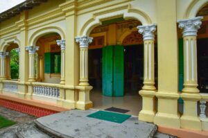 Yellow colonial façade with arched windows and pillars at Ba Duc Ancient House in Cai Be