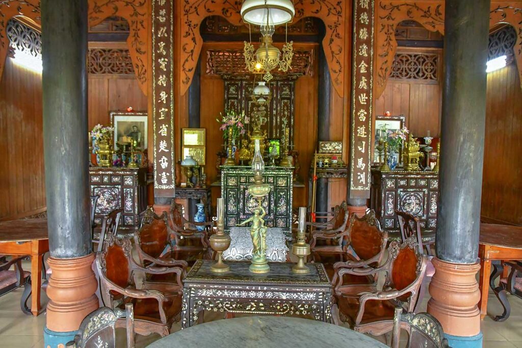 Traditional wooden interior with antique altar and carved furniture at Ba Duc Ancient House
