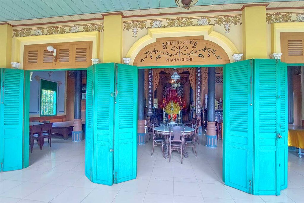 Main doorway with green shutters leading into the historic interior of Ba Duc Ancient House