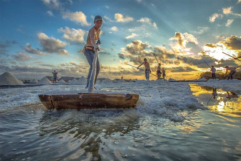A local worker uses a kind of rake to rake all the salt together at the Bac Lieu Salt Fields
