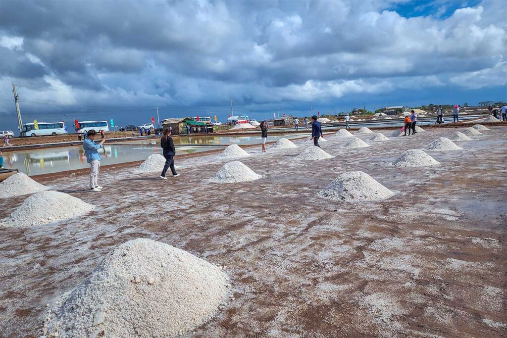 Tourists walking through piles of salt at the Bac Lieu Salt Fields