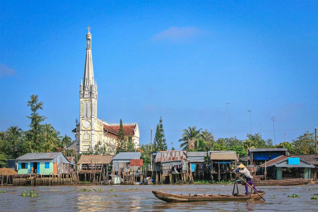 The river with small boats in Cai Be with on the riverbank the iconic Cai Be Church