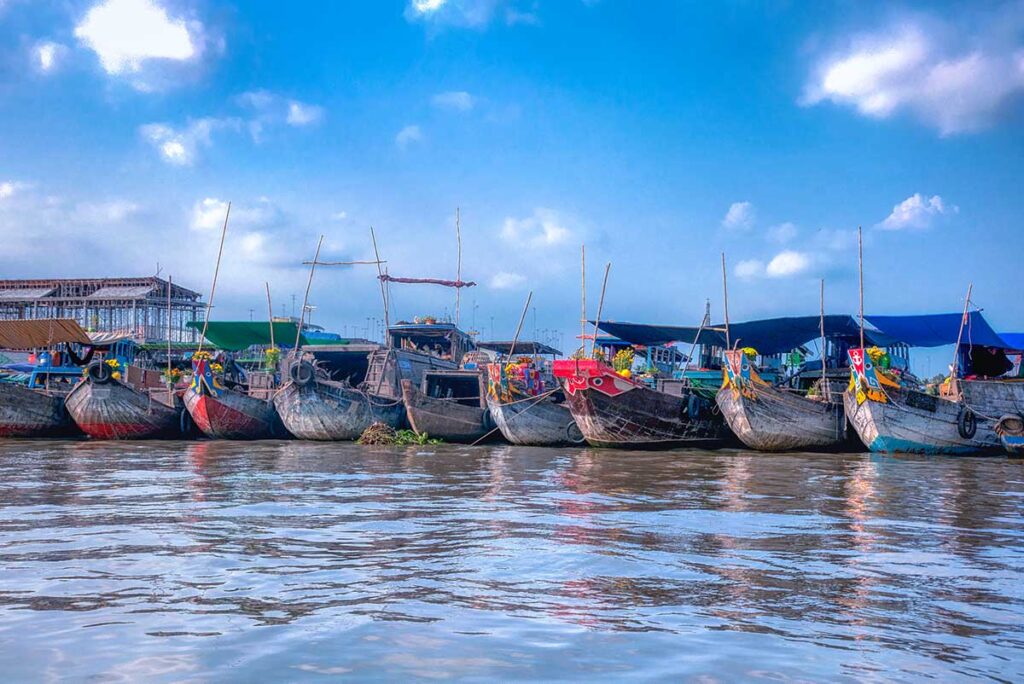 Row of trading boats lined up on the river at Cai Be Floating Market in the Mekong Delta