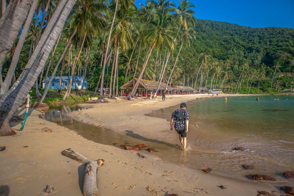 Cay Men Beach with palm trees and shacks – The main sandy stretch on Nam Du Island, shaded by coconut palms with casual food shacks along the shore.