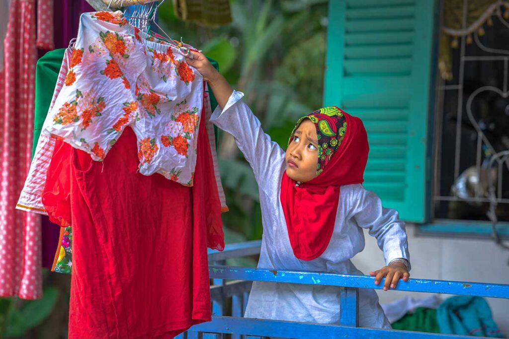 A girl hanging clothes to dry at her stilt house in Cham Village near Chau Doc