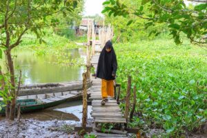 A muslim girl walking over a wooden boardwalk in Chau Giang Cham Village near Chau Doc
