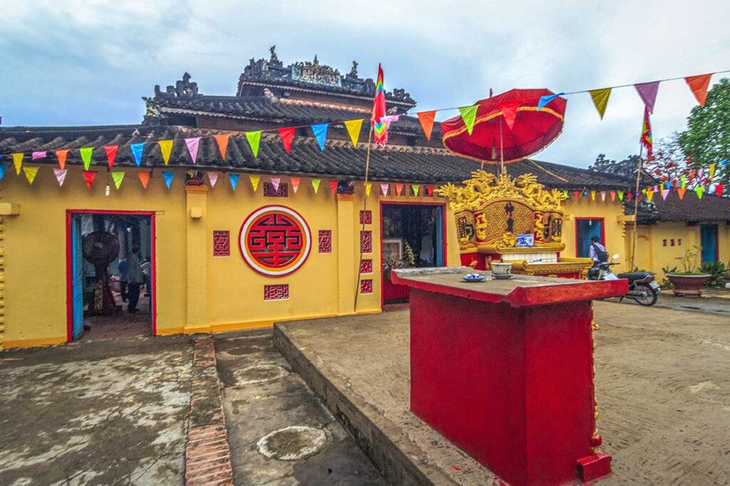 Exterior of Dinh Yen Temple (communal house) decorated with colorful flags and traditional motifs in Dong Thap, Vietnam