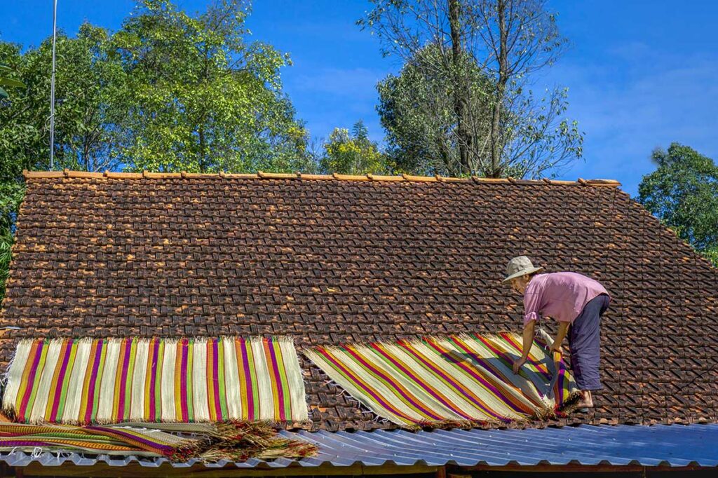 Finished mats drying on a tiled roof under the sun at Dinh Yen Mat Weaving Village in Dong Thap Province