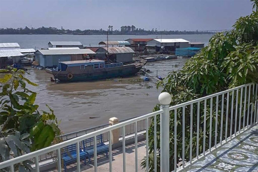 Balcony view of floating houses and fishing boats on the Tiền River from a homestay on Dragon Island (Tân Long).