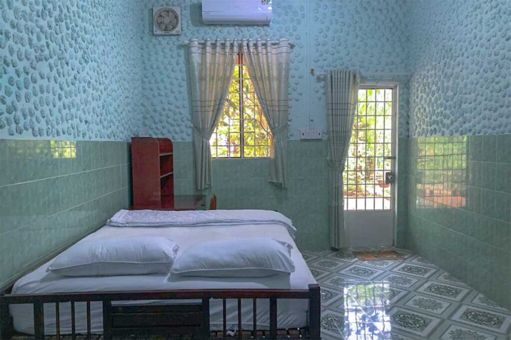 Basic homestay room with tiled walls and simple furnishings on Dragon Island (Tân Long), My Tho, Vietnam.