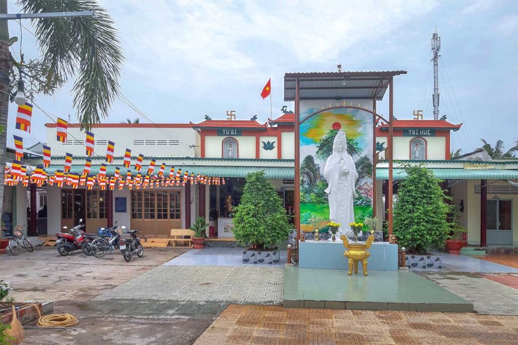 Tịnh Xá Ngọc Tân Long Pagoda with Buddhist flags and statue courtyard on Dragon Island (Tân Long), My Tho.