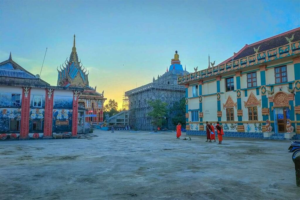 The temple grounds with monks in orange robes at Ghositaram Temple in Bac Lieu