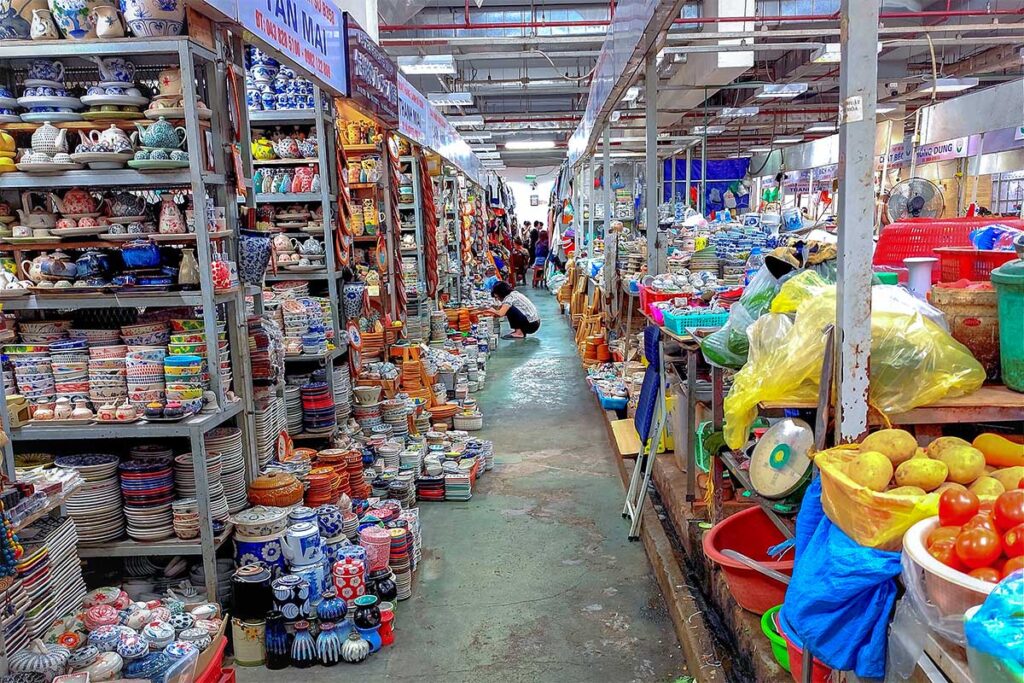 Stalls with pots and ceramics on one side and on other side of the aisle fruits, vegetables and prepack food inside Hang Da Market