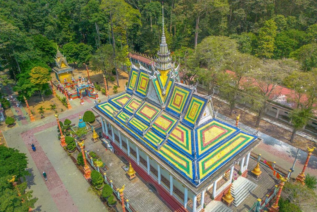 Aerial view of Hang Pagoda complex in Tra Vinh, showing the vibrant tiled roof and surrounding greenery.