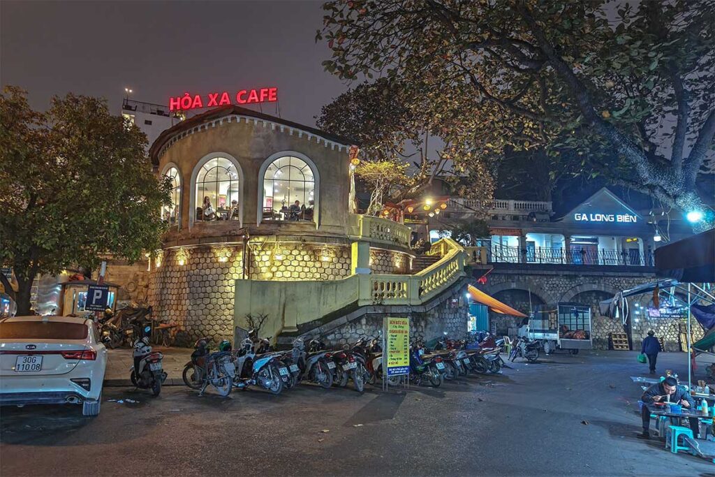 Nighttime view of Hoa Xa Café and Long Bien Train Station next  to each other 