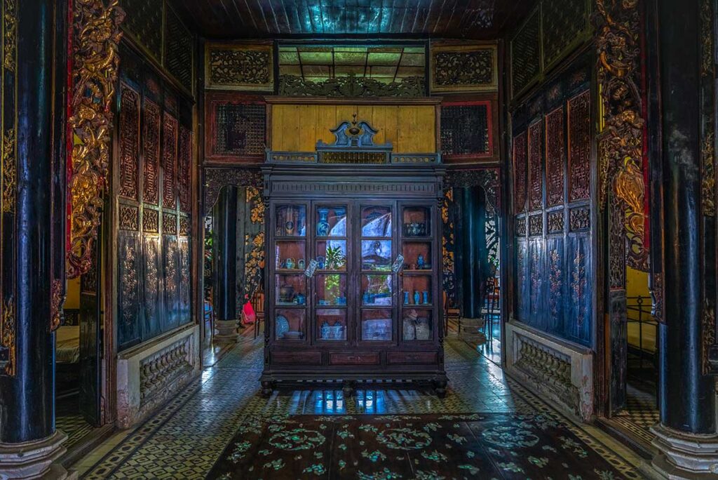 Ornate wooden panels and antique cabinet inside Huynh Thuy Le Ancient House, Dong Thap Province