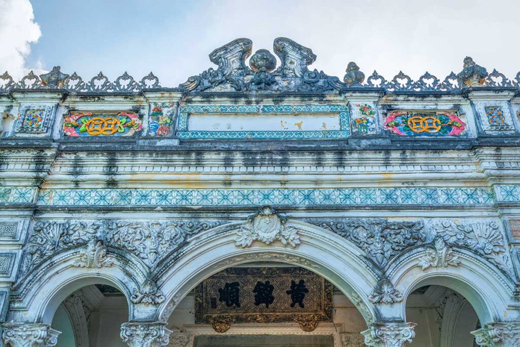 French-style façade with arched entrance and decorative tiles of Huynh Thuy Le Ancient House in Sa Dec